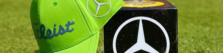 ein grünes Basecap und ein Glas Sekt auf einem Würfel mit Mercedes-Benz Logo