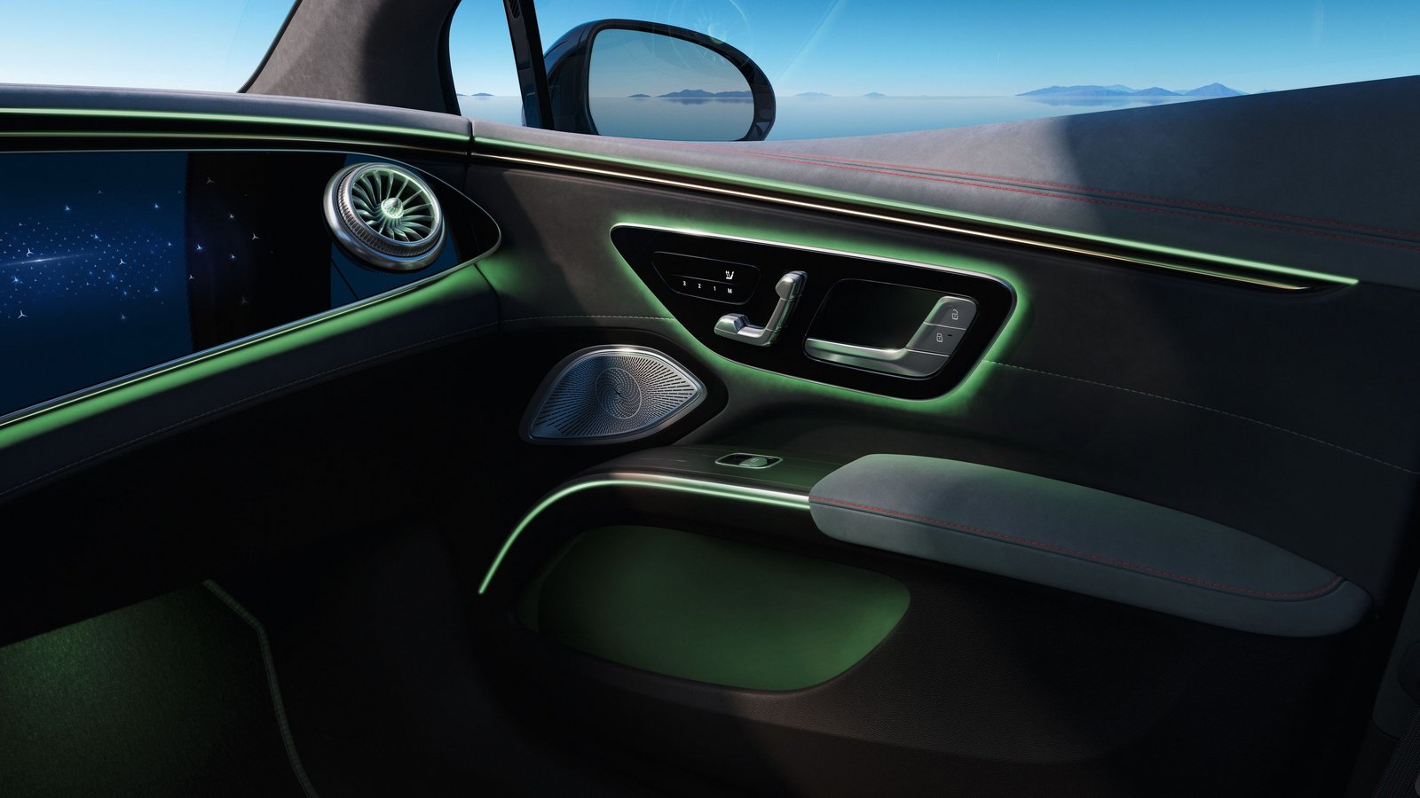 Türverkleidung des Mercedes-Benz EQS mit grüner Ambientebeleuchtung und modernem Bedienpanel vor einer Berglandschaft.