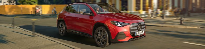 Roter Mercedes-Benz GLA elektrisch fährt auf einer Straße in urbaner Umgebung mit modernen Gebäuden im Hintergrund