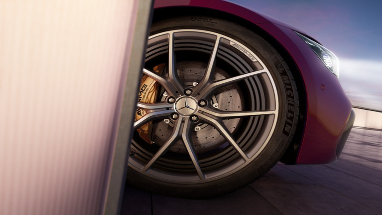 Nahaufnahme der AMG Felge eines Mercedes-AMG Modells, das die edle Alufelge mit markanten Linien und die goldfarbenen Bremssättel zeigt, unterstrichen durch die Michelin Hochleistungsreifen.